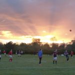 People playing football as the sun sets
