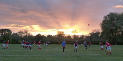People playing football as the sun sets